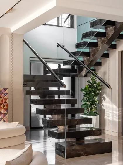 A staircase can be more than just a connection between floors; it can be the home's sculptural heart. This floating staircase, crafted from a single block of marble, appears to defy gravity. It’s a testament to precision engineering and our commitment to creating breathtaking architectural moments.