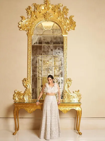 A full-length shot of the white Manish Malhotra lehenga against a grand, ornate mirror, emphasizing its sophisticated and luxurious feel.