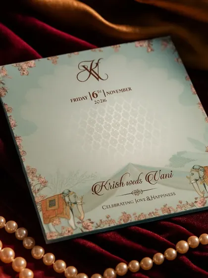 This design offers a fresh take on traditional motifs, using a calming light blue and pastel pink color palette. The card features subtle elephant illustrations and a delicate floral border, perfect for a sophisticated day wedding.