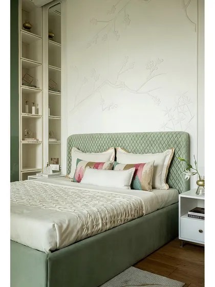 In this serene green bedroom, a nature-inspired handmade 3D wall mural sits behind the bed. The room celebrates craftsmanship and speaks of luxury subtly, with details like 11-foot tall lacquered glass wardrobe shutters and gold accents.