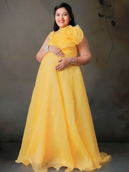 Shine bright in our yellow organza gown. The vibrant color and oversized statement flower create a cheerful and unforgettable look for your maternity photos.