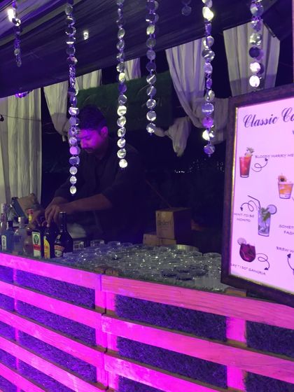 A rustic bar with a pink illuminated pallet wood front, perfect for a chic and casual event.