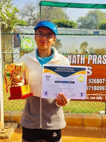 Khushi Sharma holding her trophy and certificate of merit after winning the CS7 U-14 girls' singles title.