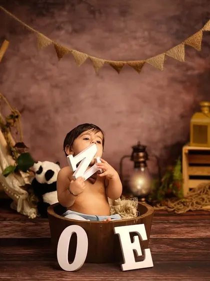 Exploring the setup before the cake arrives. This little one is enjoying the props in our jungle-themed first birthday session, holding the letters that spell out "ONE".