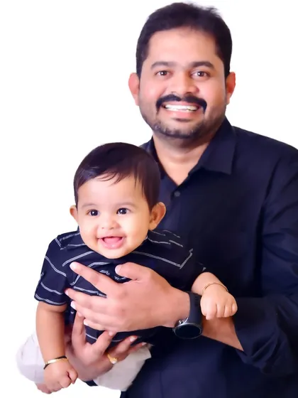 A proud father holds his smiling baby boy. This clean, classic studio portrait against a white background puts all the focus on their happy expressions and the bond they share.