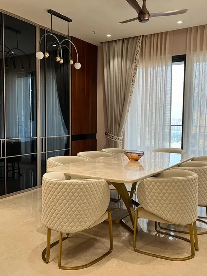 This dining space combines elegance with modern design. We paired a sleek marble tabletop with quilted cream chairs and brass accents, while the smoked glass wardrobe provides a reflective, space-enhancing backdrop.
