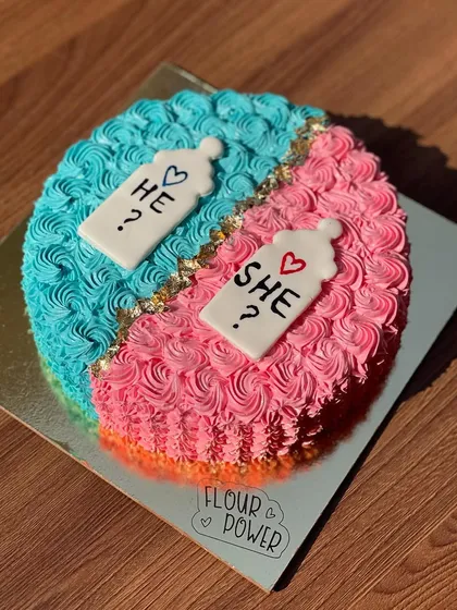 A "He or She?" gender reveal cake, split down the middle with blue and pink buttercream. It's a sweet way to build anticipation for the big reveal.