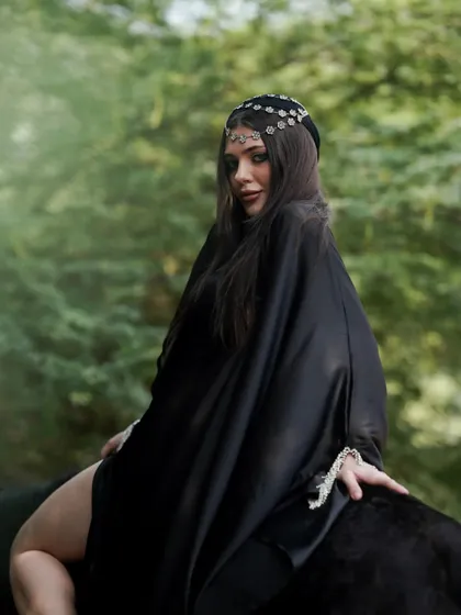 The color version of a shot from the Arabic-themed series, showing the model in a black robe against the lush green background.