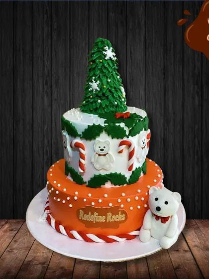 Another take on a Christmas theme, this two-tier cake features a buttercream Christmas tree topper and a cute fondant polar bear. The design combines classic holiday elements like candy canes and holly leaves.