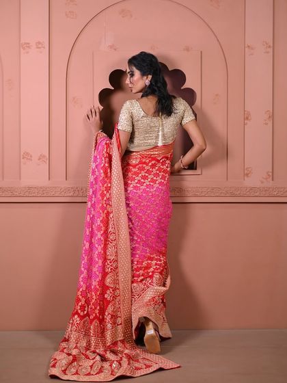 The flowing elegance of a red and pink ombre saree with a heavy brocade border, a perfect statement piece for any celebration.