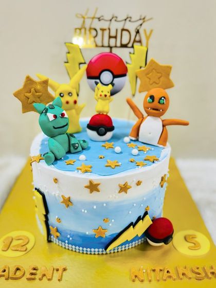 Gotta catch 'em all! This vibrant Pokémon cake features fondant figures of Pikachu, Charmander, and Bulbasaur, complete with Poké Balls for a budding Pokémon trainer.