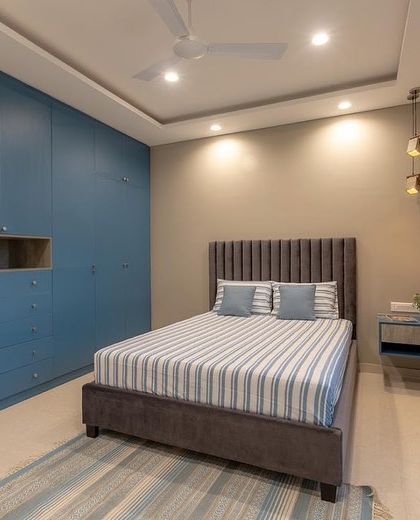 The final result of the guest bedroom design, with a striking blue wardrobe and a comfortable, inviting bed.