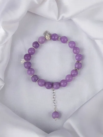 A purple beaded bracelet with a dangling charm and silver accents.