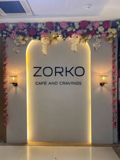 The entrance of Zorko Cafe framed with cascading artificial flowers. This creates a beautiful and inviting entryway that looks great both day and night.