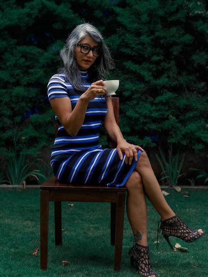 A seated portrait in the striped dress, creating a chic and intellectual vibe.