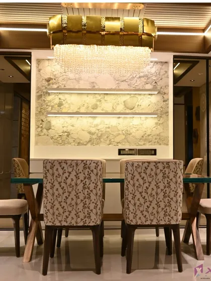 A luxurious dining area featuring a stunning crystal chandelier as the centerpiece. The back wall combines a textured marble panel with backlit shelves, creating a sophisticated backdrop for family meals and gatherings.