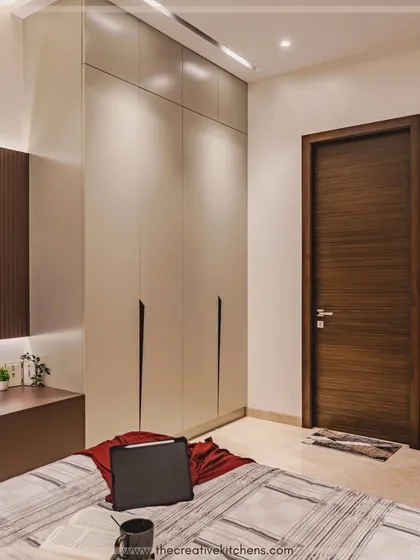 Another view of the matte lacquer wardrobe, showing how it integrates with the bedroom's overall aesthetic. Its clean, unobtrusive design complements the modern TV unit and warm tones of the room.