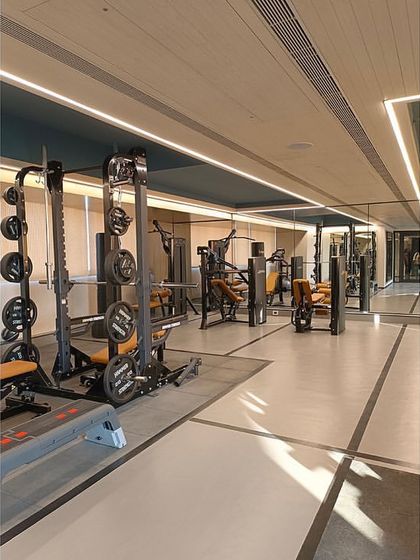 The fully-equipped gym at 'The Bandra Project'. The design uses a grey vinyl floor with black line details, while the ceiling coves are painted blue to add a dynamic element to the workout space.