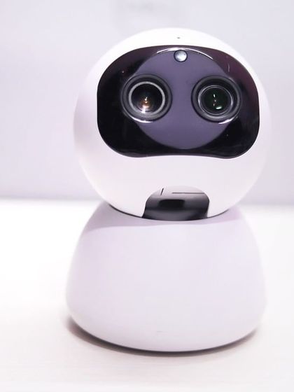 A close-up of the dual-lens AI HD IP Camera. This innovative design combines a wide-angle and telephoto lens to provide both a broad overview and detailed zoom capabilities.