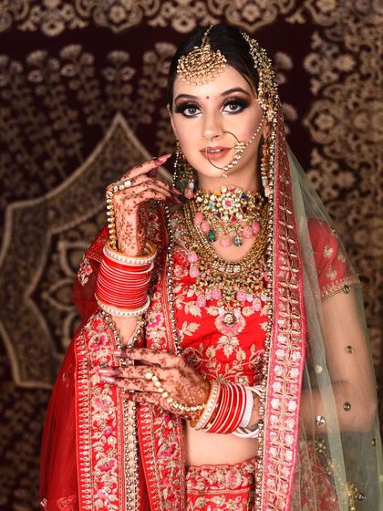 Our client looks picture-perfect in this vibrant red floral embroidered lehenga. The multi-layered pastel beaded jewellery set adds a contemporary touch to the traditional outfit.