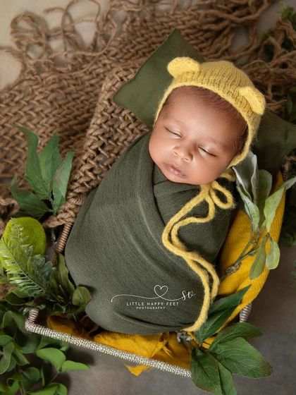 A cozy, wrapped baby in a basket. The earthy green and yellow tones and the simple, natural props create a feeling of warmth and comfort.