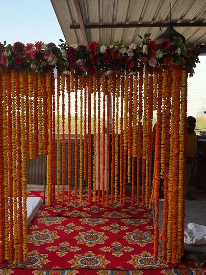 The marigold string mandap viewed from the side, showing the structure and the seating arrangement inside.