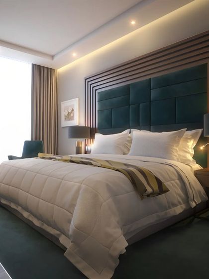 We created a hotel-like experience in this bedroom with a custom-designed headboard. The large, tufted green headboard is framed by wood paneling with geometric patterns, providing a look of classic luxury and comfort.