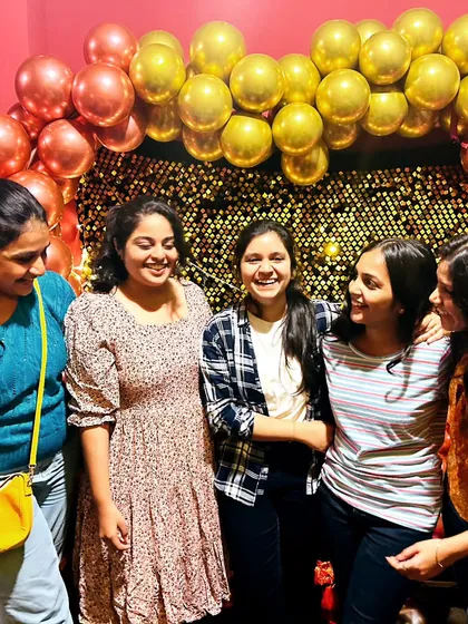 Candid moments are the best. A group of friends sharing a laugh in front of the decorated photo wall.