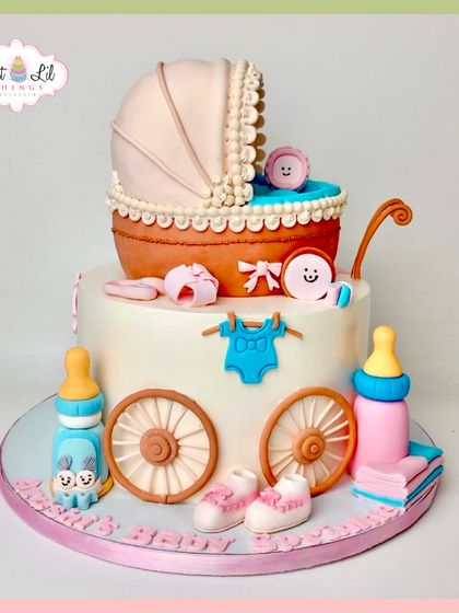 A classic and adorable baby shower cake. This two-tiered design features a vintage-style pram, baby shoes, bottles, and other sweet details.