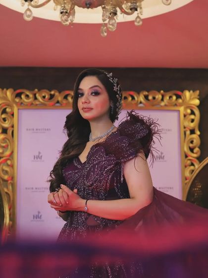 An elegant portrait of a woman in a glamorous purple gown for an evening event. The flowing fabric and sophisticated pose create a look of high fashion and grace.