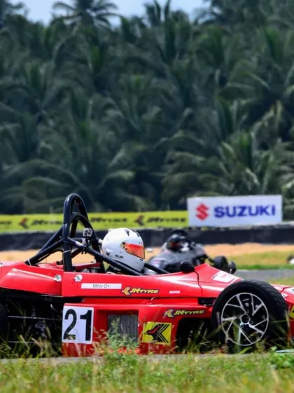 The number 21 Formula LGB car at speed, framed by the lush greenery of the Kari Motor Speedway.