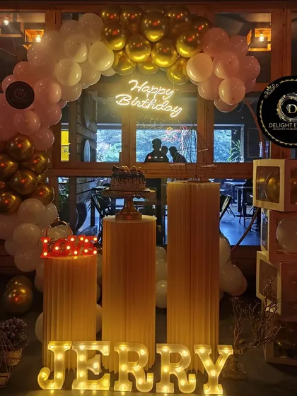 We can turn your favorite cafe into a personalized party zone. This setup includes our popular balloon arch in gold and pink, illuminated marquee letters for a custom name, and display pedestals for the cake and gifts.