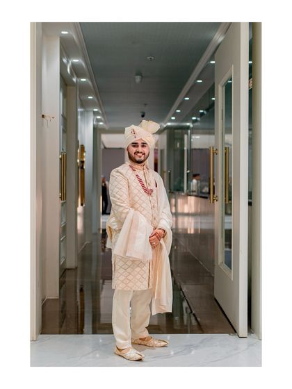 A classic portrait of the groom standing in a well-lit hallway, looking sharp and ready for his wedding.