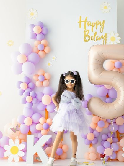 Five and fabulous. Her cool sunglasses and confident pose show off her budding personality against the fun birthday backdrop.
