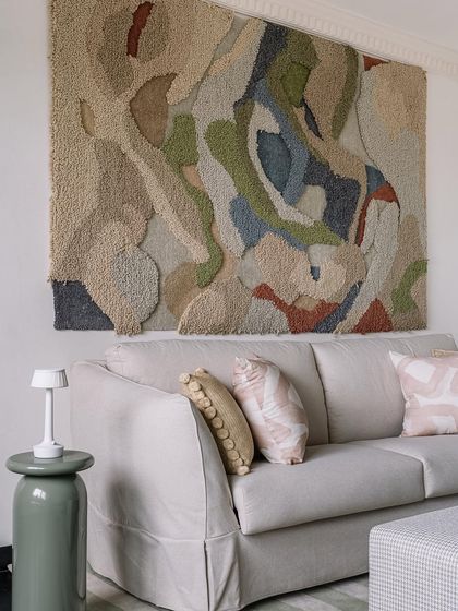 The home office lounge features a large, textural art piece and a comfortable sofa, making it an inspiring place to work or relax.