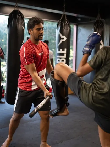 A student practices checking a low kick, a fundamental defensive move in Muay Thai to protect the legs from damage.