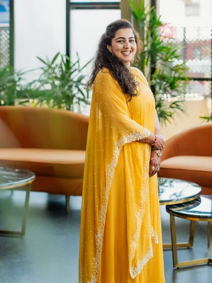 A full-length shot of the sister of the bride in her vibrant yellow Haldi outfit. The flowing silhouette and delicate embroidery make it a perfect choice for a daytime celebration.