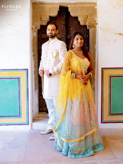 Couple goals. Slay your pre-wedding shoot with coordinated outfits that tell your love story. This vibrant multi-color lehenga and classic ivory sherwani create picture-perfect memories.