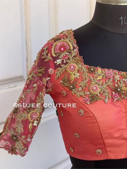 A beautiful peach-colored blouse with sheer net sleeves. The sleeves are embroidered with a delicate floral vine pattern in zardozi and pink threadwork, creating a romantic and ethereal effect.