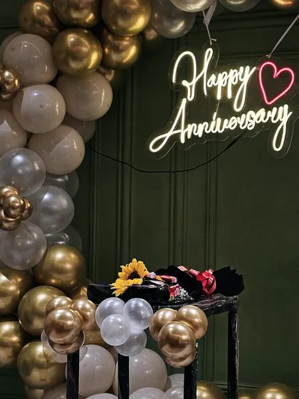 A detailed shot of the anniversary decor, showing the bouquet placed on a stand next to the balloon arch.