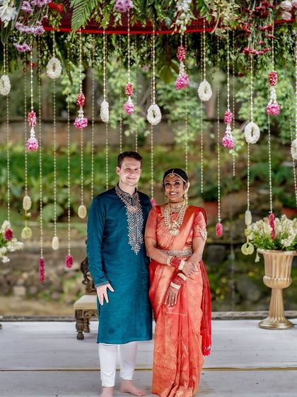 A formal portrait of a couple under a floral arch, showcasing a classic wedding setup.