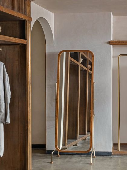 A freestanding mirror with a wooden frame and brass details adds a touch of vintage elegance to the Eka store. Every piece of furniture was either custom-designed or carefully sourced to align with the brand's narrative of heritage and craft.