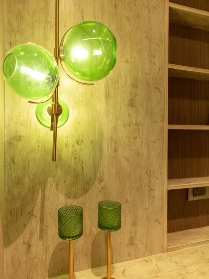We love using color in our lighting choices. This green glass wall lamp, paired with matching candle holders, creates a cohesive and stylish vignette against a textured wood wall.