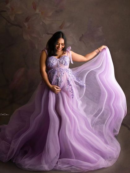 The joy is so evident in this shot. The mom-to-be playfully holds the sheer fabric of her lavender gown, smiling as she looks down.