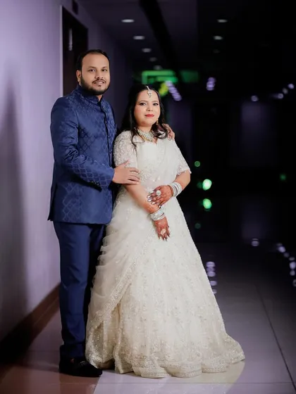 A full-length portrait of the couple in a brightly lit corridor. The groom in his royal blue suit and the bride in her elegant white gown create a striking and stylish image.