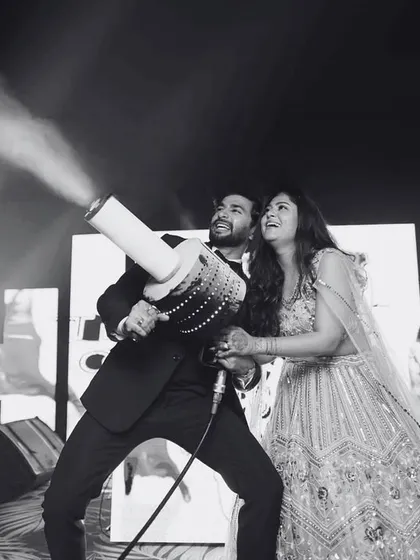 Let's make some noise! The couple takes control of the CO2 cannon, adding a blast of energy and fun to their sangeet after-party.