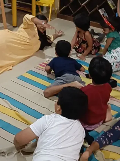 A storyteller uses playful movements and expressions to act out a scene, much to the delight of the children.