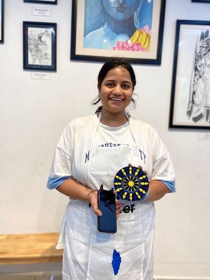 A participant with her finished dot mandala. The bright colors and precise pattern show the beautiful results of this meditative craft.