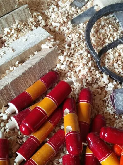 A pile of colorful wooden whistles, waiting for the final assembly. These simple, classic toys are a nostalgic favorite and demonstrate how even the smallest items are crafted with care and attention to detail.