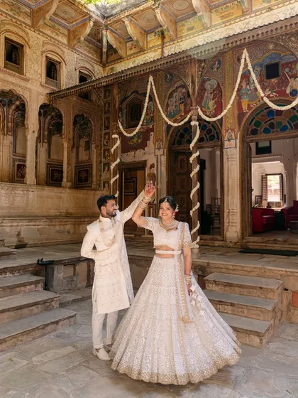A playful dance in the courtyard of a Rajasthani haveli, where the couple's white outfits stand out against the intricate architecture and traditional art.